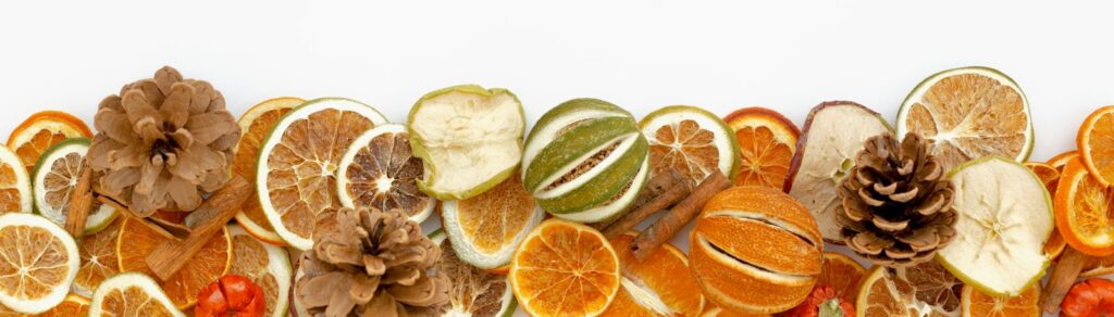 a group of sliced oranges, apples, and pine cones